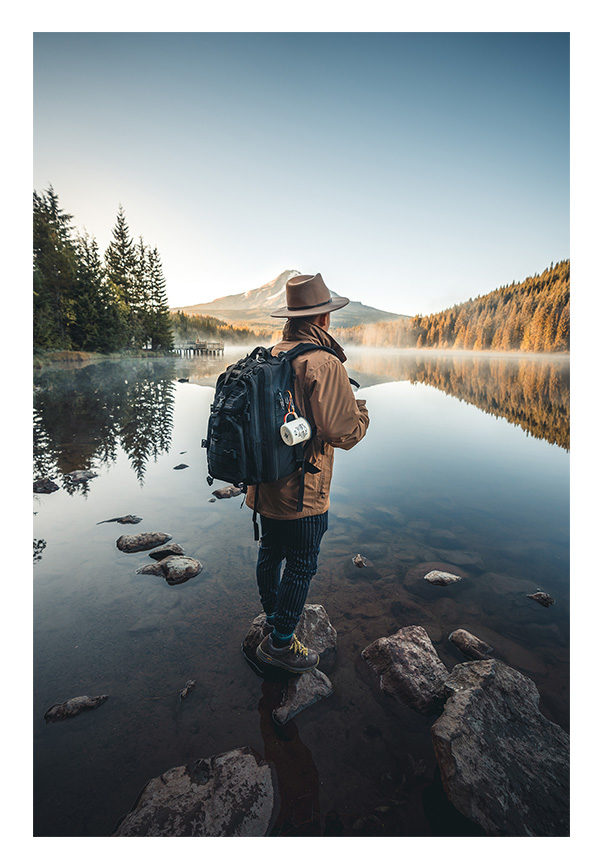 hiker looking out over lake with fog below mountains at sunrise